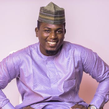 Portrait of a smiling man wearing traditional attire and cap indoors.